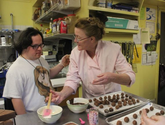 Young adult talking with a chef in front of a tray of chocolate truffles